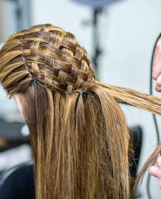 Hairstylist straightening a woven braid hairstyle on a mannequin. Hairstylist straightening a woven braid hairstyle on a mannequin.